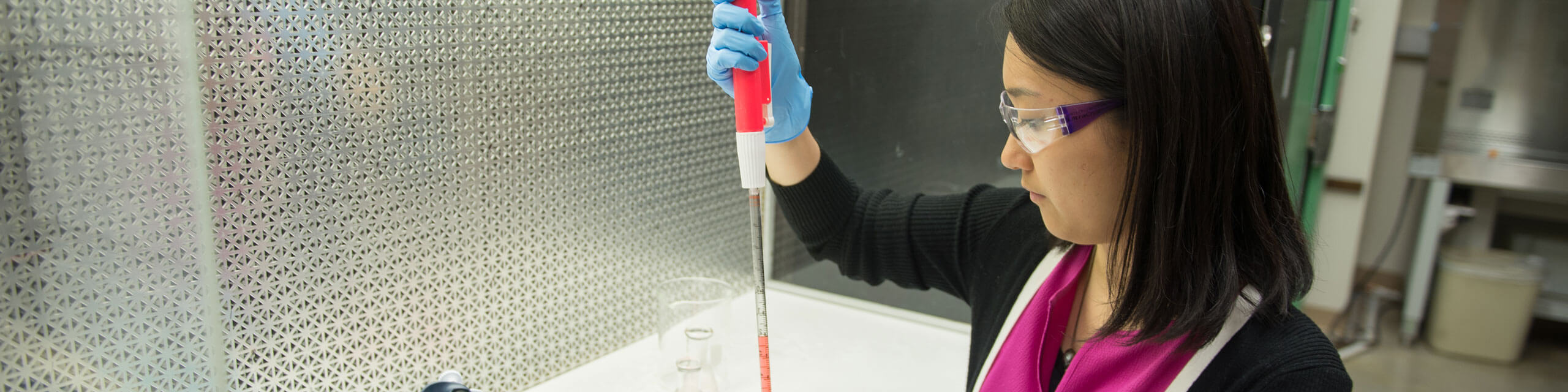 Nurse fills a beaker in a lab.