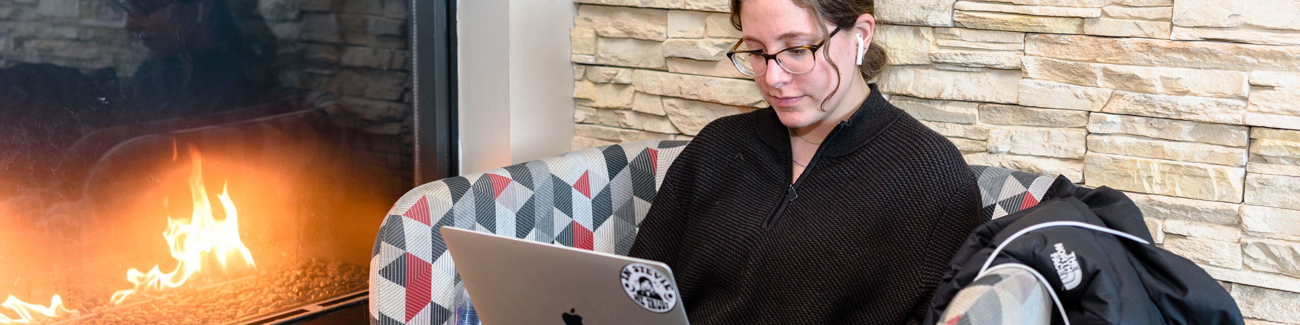 Student sitting in an armchair, studying on her laptop.