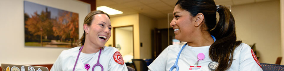 Two nursing students smile as they study together.